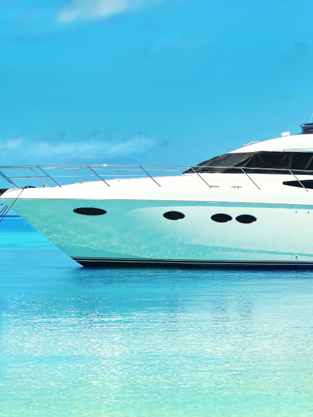 Luxury yacht anchored in clear blue waters under a bright sky.