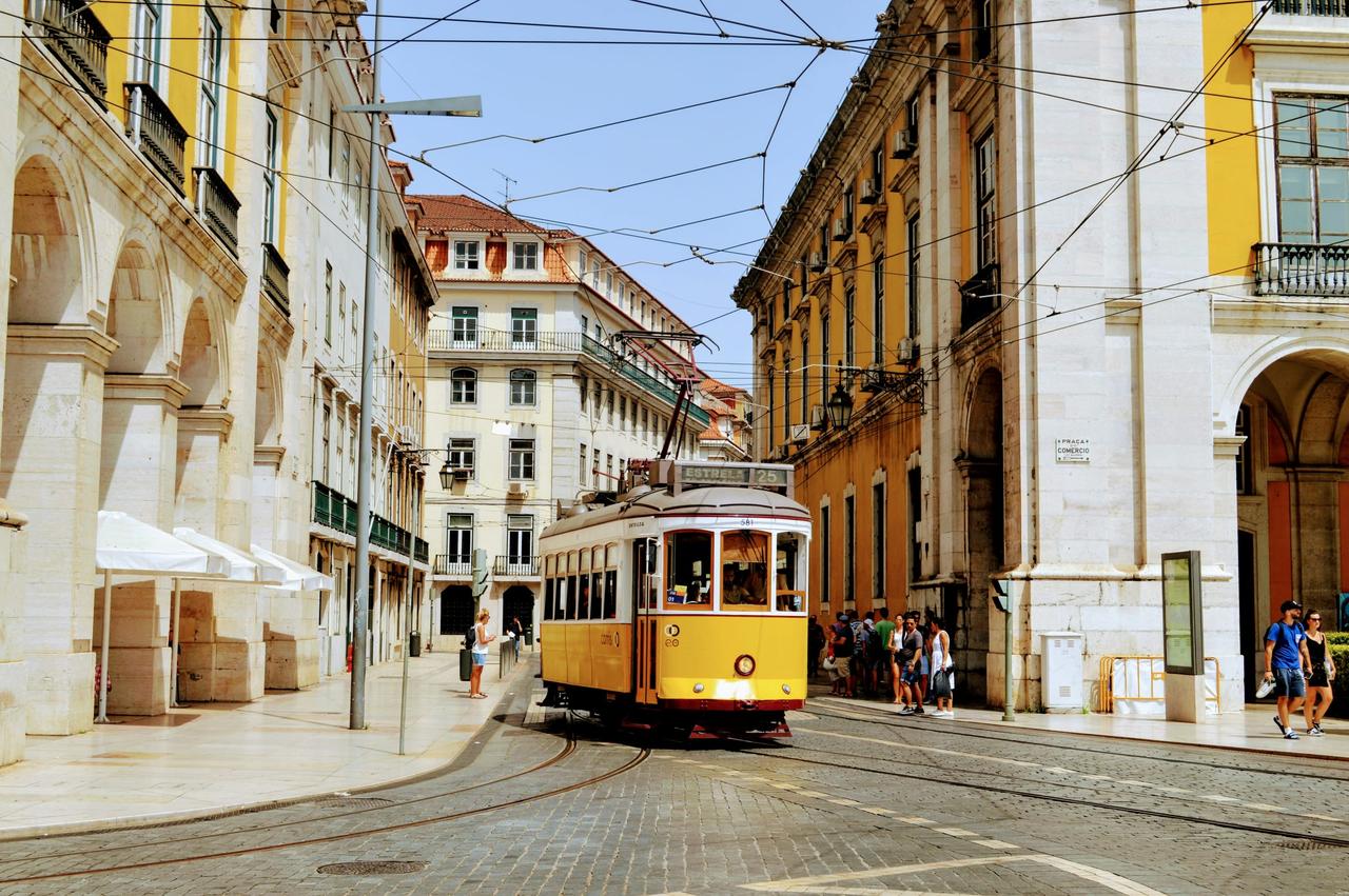Un tramway jaune circulant dans une rue pavée ensoleillée.