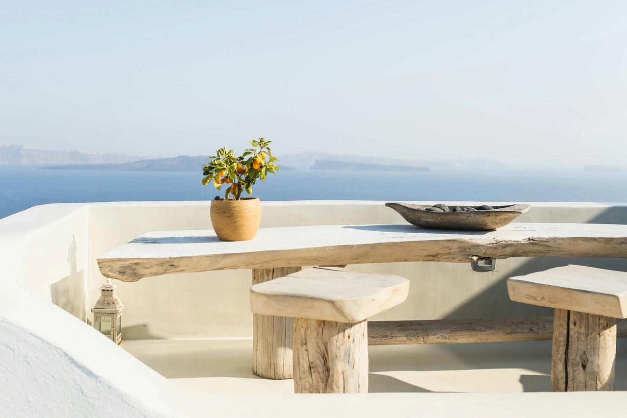 Terrasse avec table en bois et vue sur la mer.
