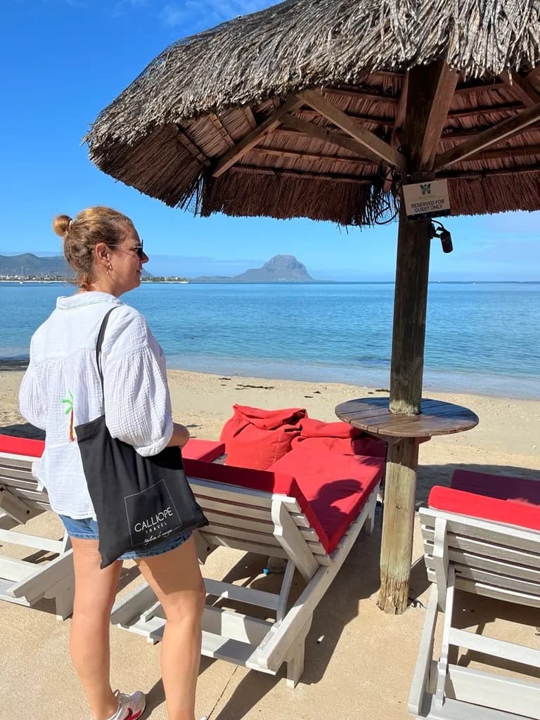 Femme regardant la mer depuis une plage avec des chaises longues.