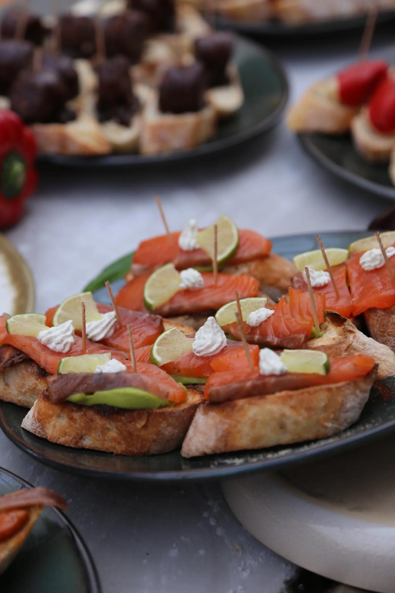 Platter of salmon appetizers with lime and cream on toasted bread.