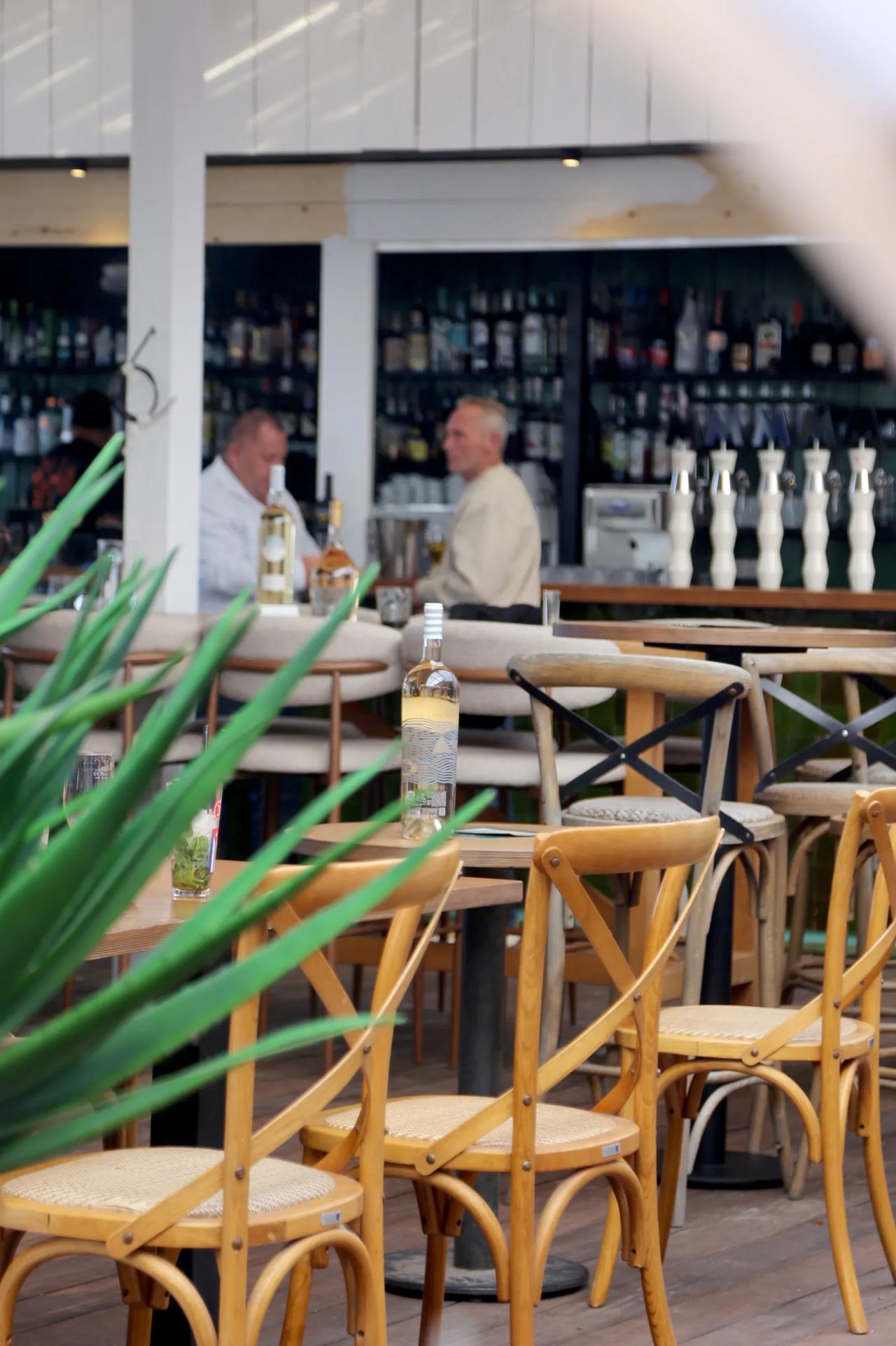 Bar scene with patrons and bottles on wooden tables