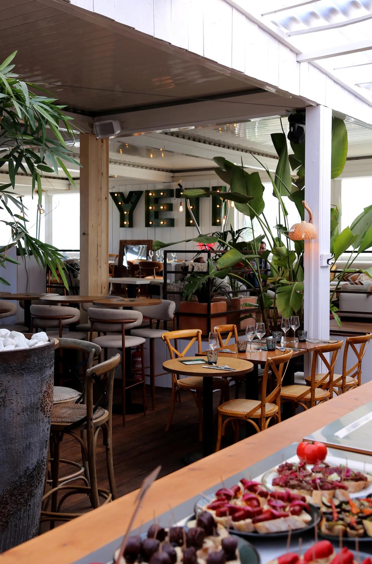 Interior view of YETI restaurant with tables and plants.