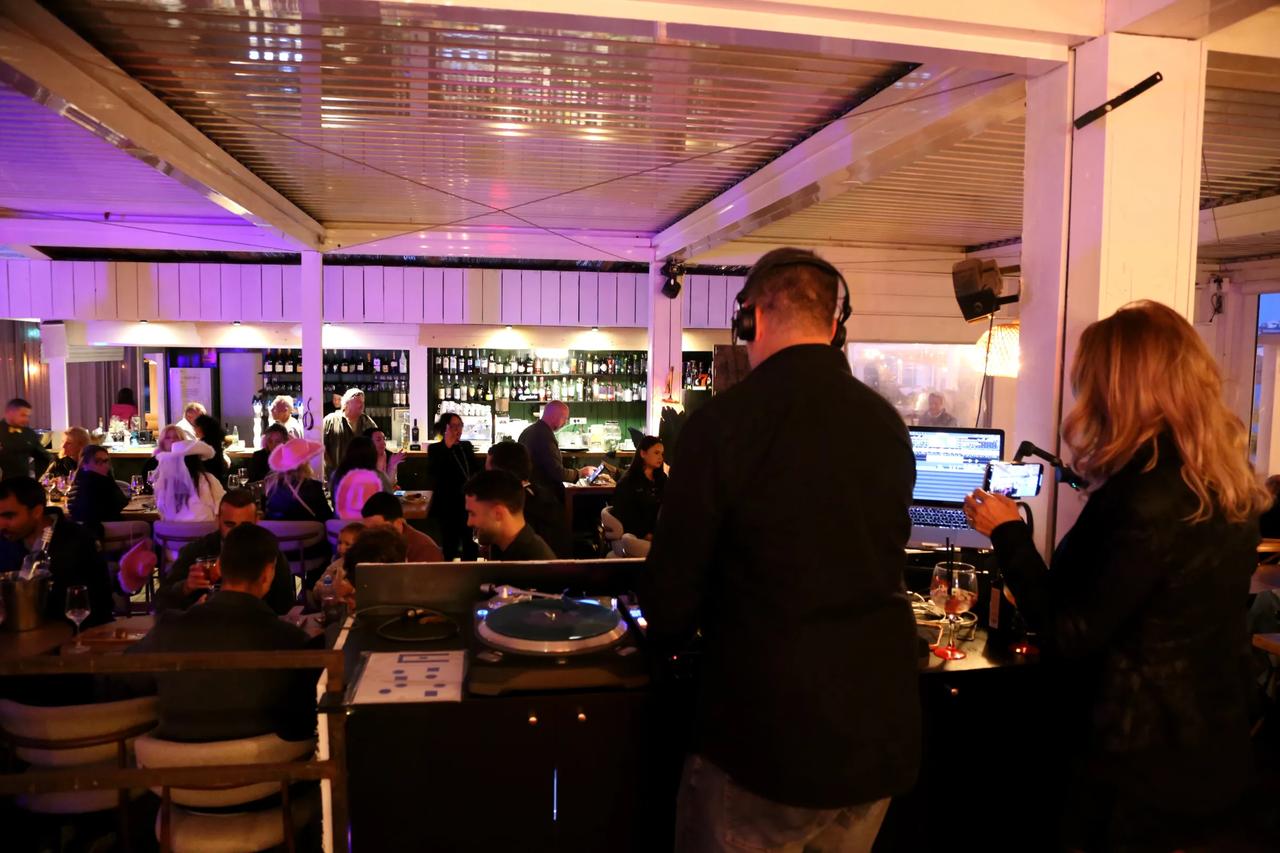 Interior view of a restaurant with a DJ and guests enjoying the atmosphere.