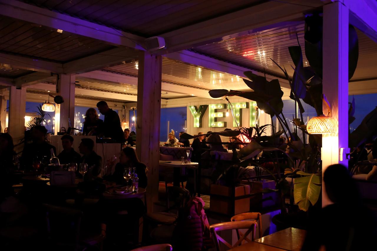 Interior view of YETI restaurant with illuminated sign and patrons.