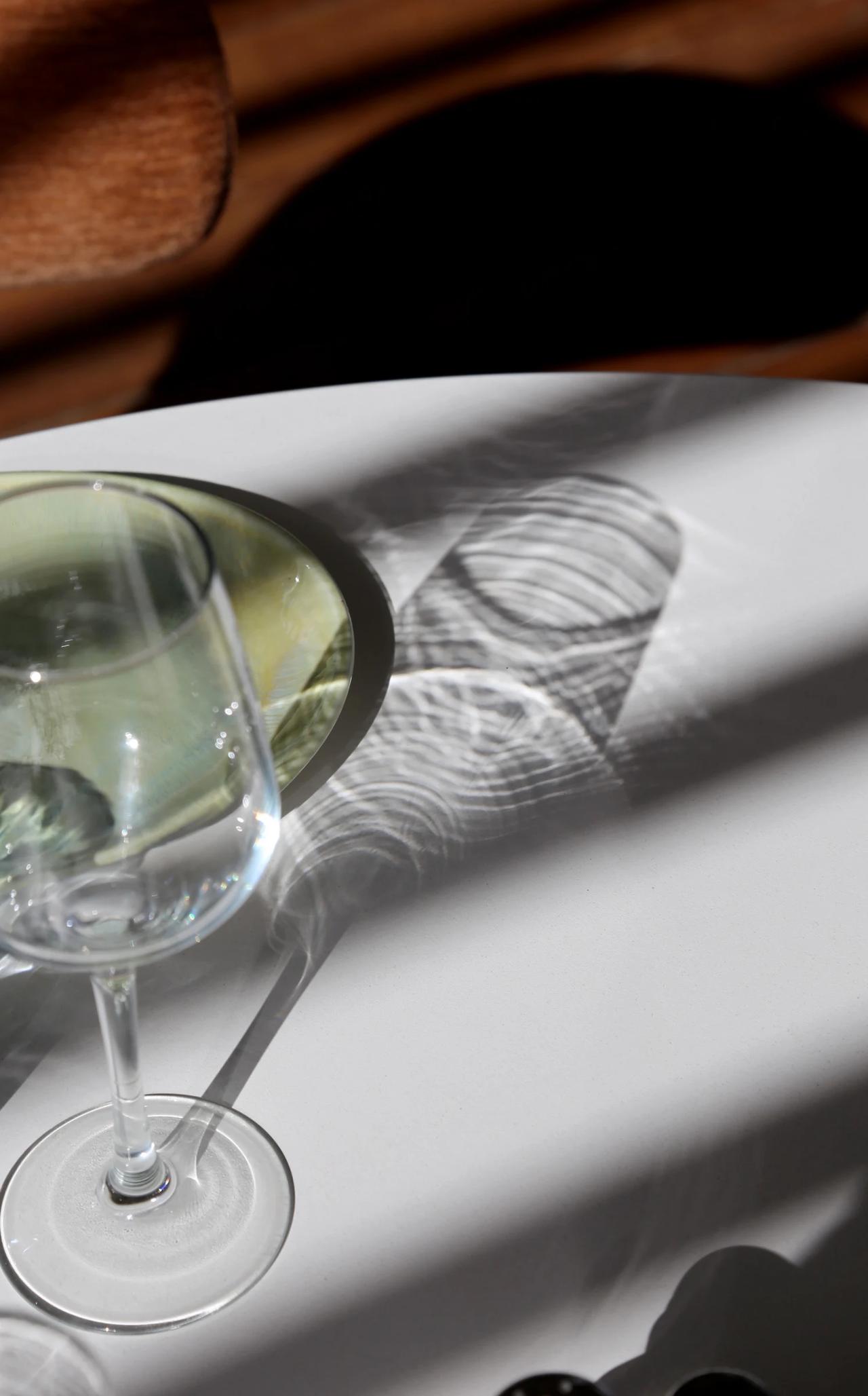 A glass and a plate casting shadows on a table.
