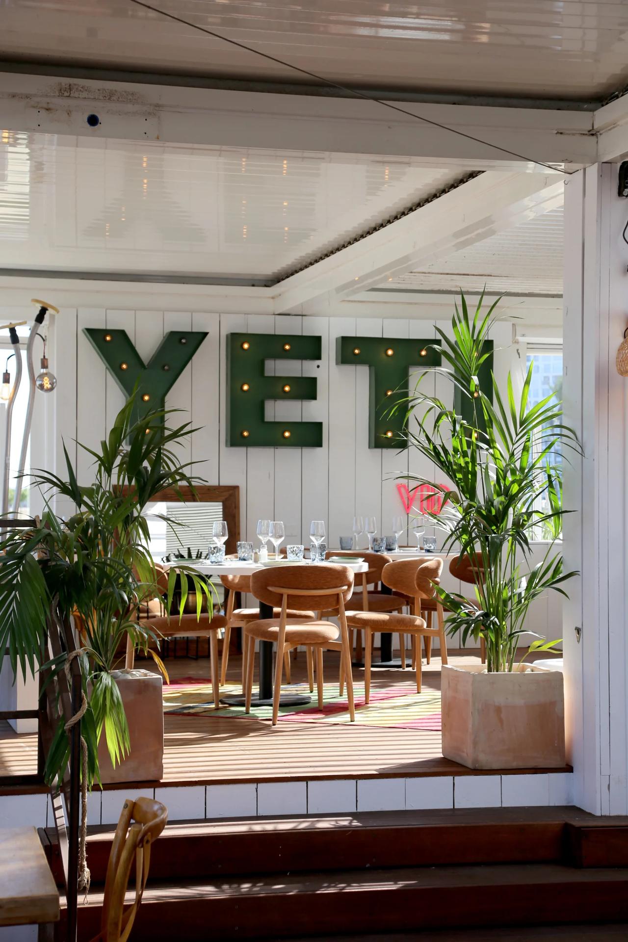 Interior view of YETI restaurant with green letters and plants.
