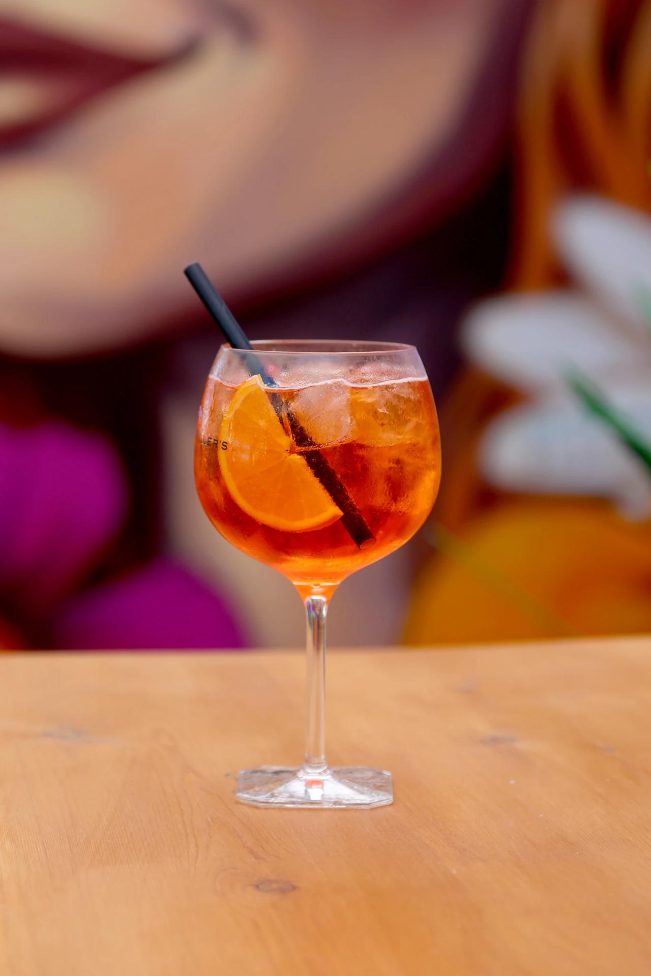A refreshing cocktail with orange slices and ice in a glass.
