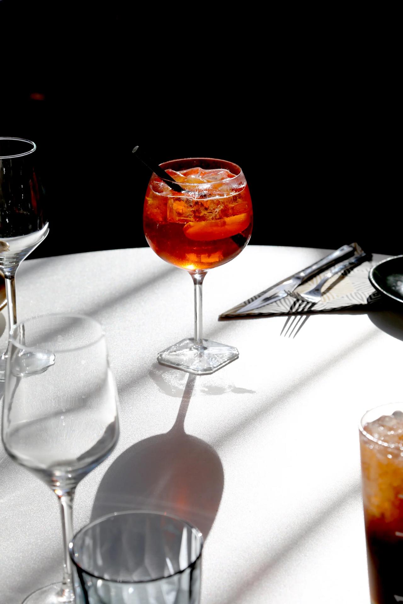 A cocktail glass with a straw and citrus slices on a table.