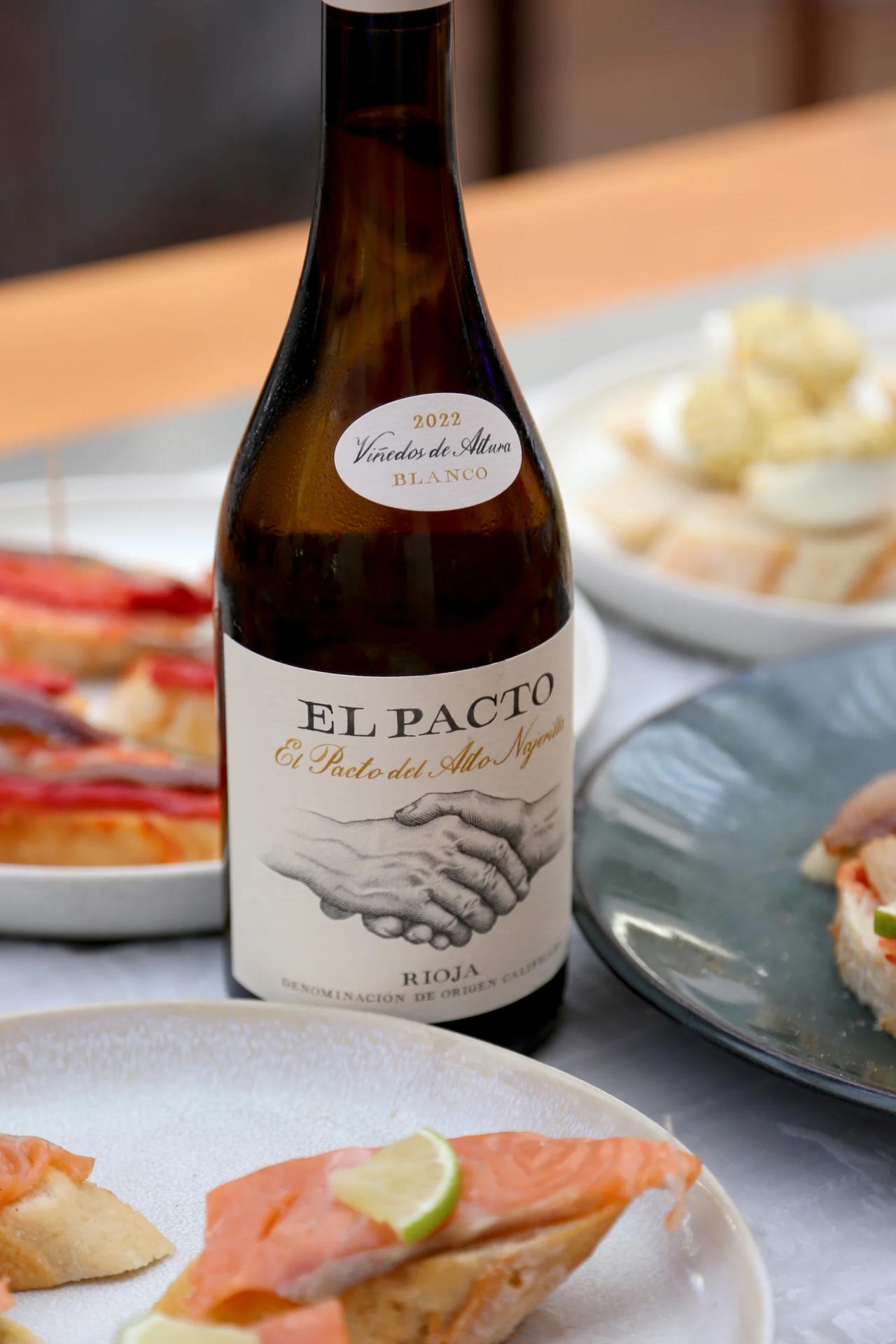 Bottle of El Pacto wine with tapas on a table