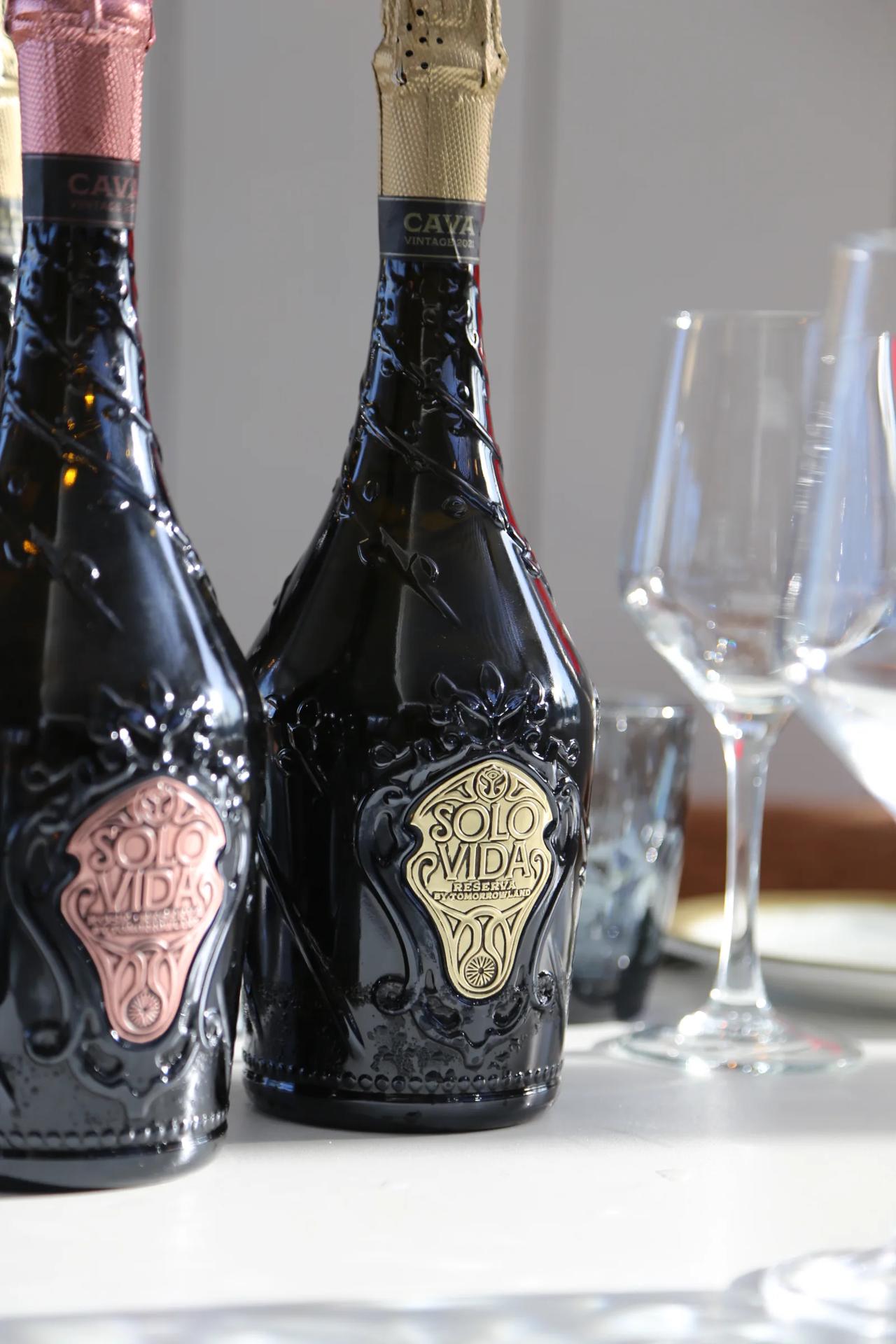 Two bottles of Solo Vida cava with glasses in the background