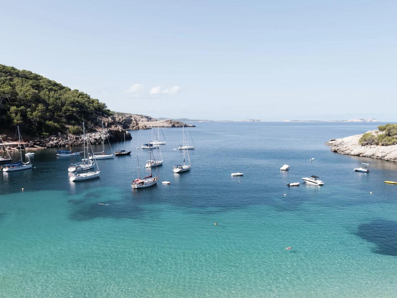Sailboats anchored in a tranquil bay surrounded by greenery.