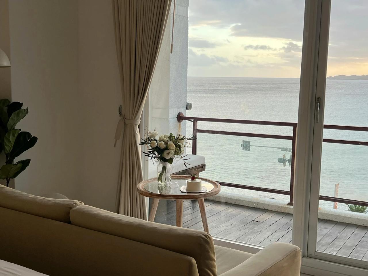 Cozy interior with a view of the ocean and a flower arrangement on a table.