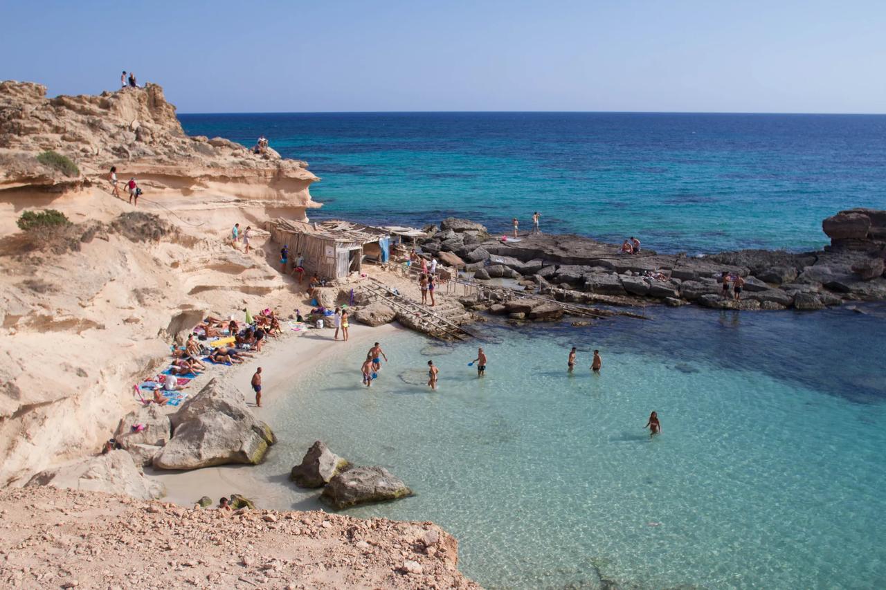 Clear turquoise waters at a beach with rocky cliffs.