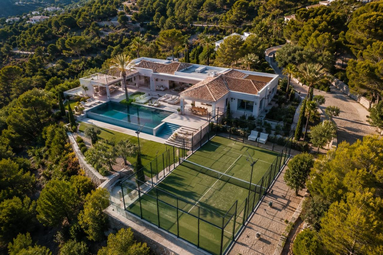 Aerial view of a modern villa with a swimming pool and tennis court.
