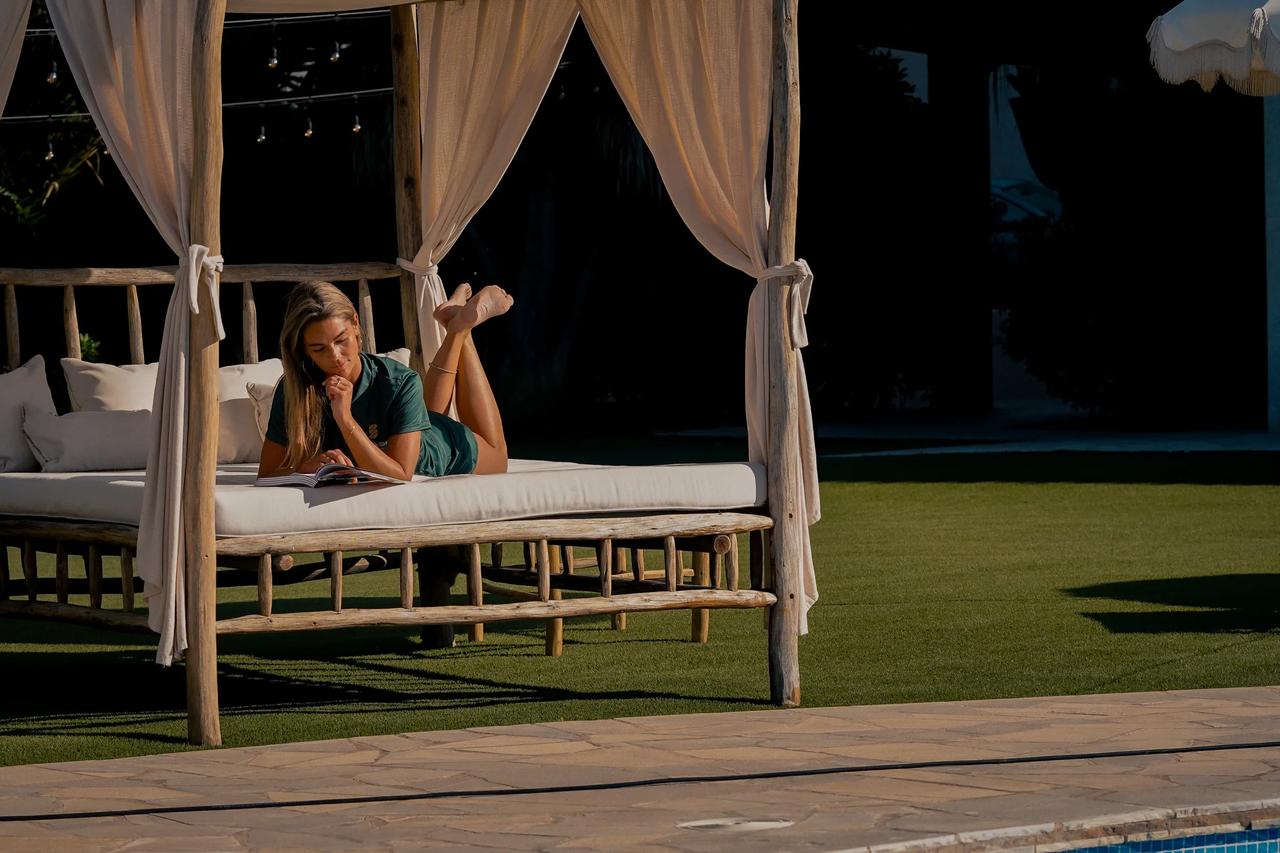 Woman reading a book on a sunbed by the pool.