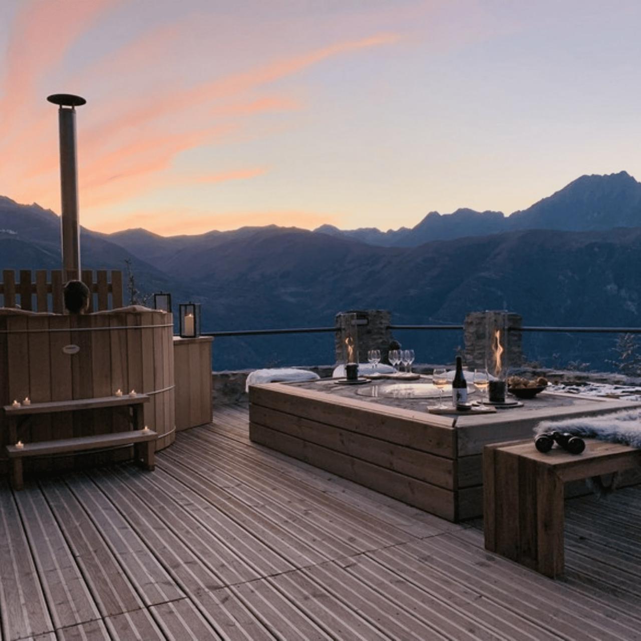 Terrasse en bois avec vue sur les montagnes au coucher du soleil.