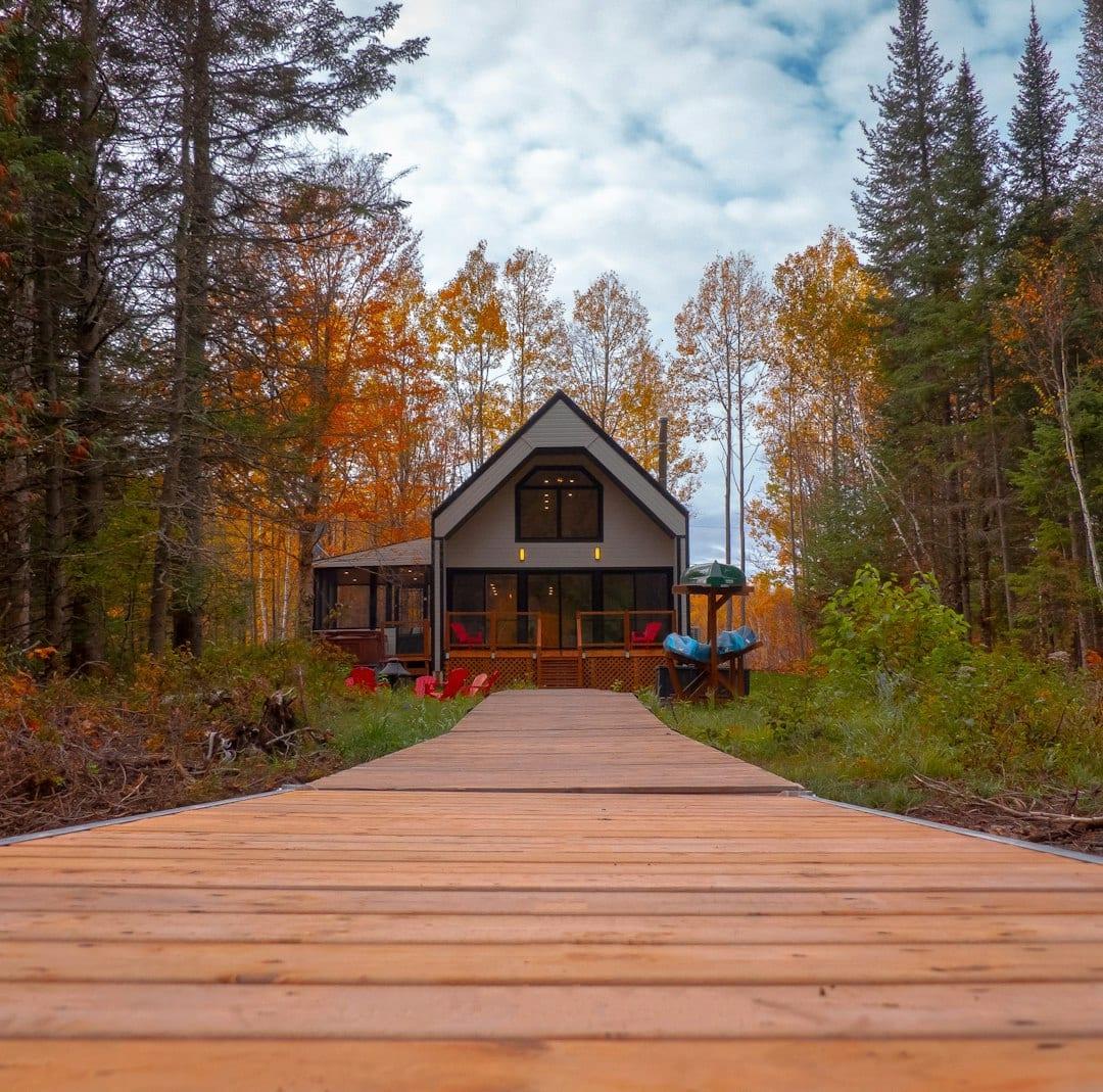 a wooden walkway leading to a house in the woods dcbnLKvsuHo