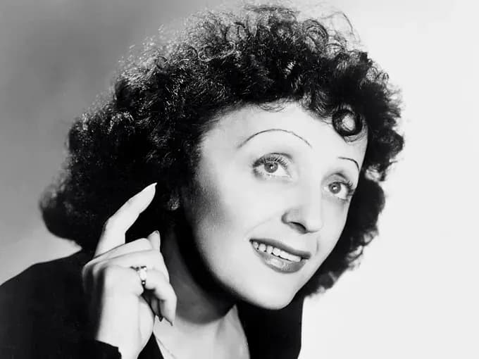 Femme avec des cheveux bouclés, souriant et pointant un doigt vers le haut.