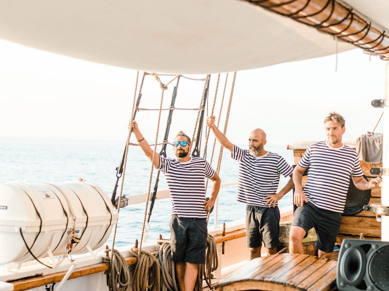 Three men in striped shirts on a boat, enjoying the sea view.