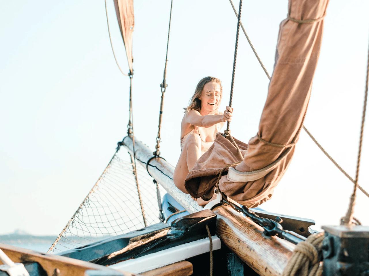 A person enjoying sailing on a boat with sails raised.