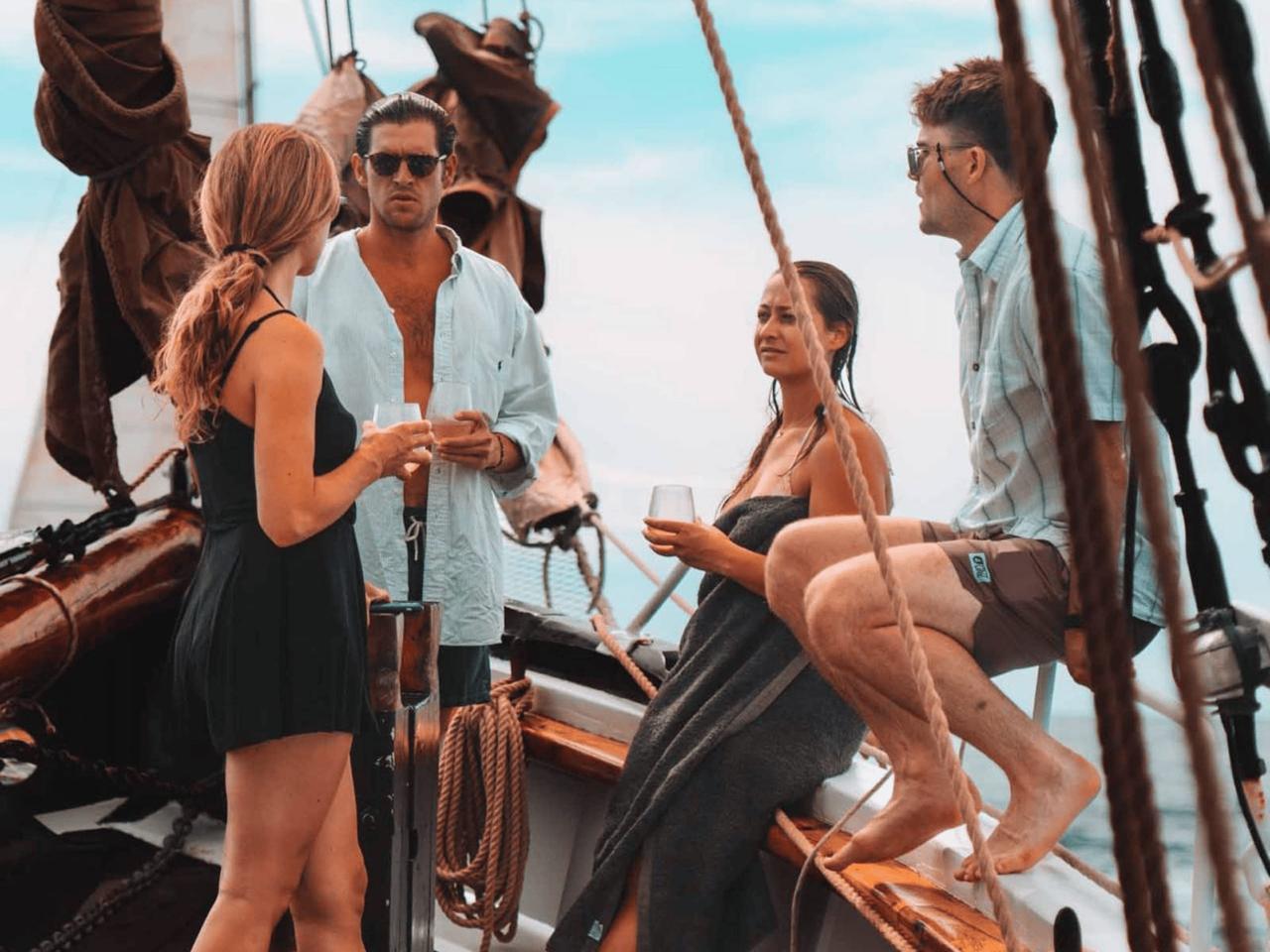 Group of four people enjoying drinks on a sailboat.