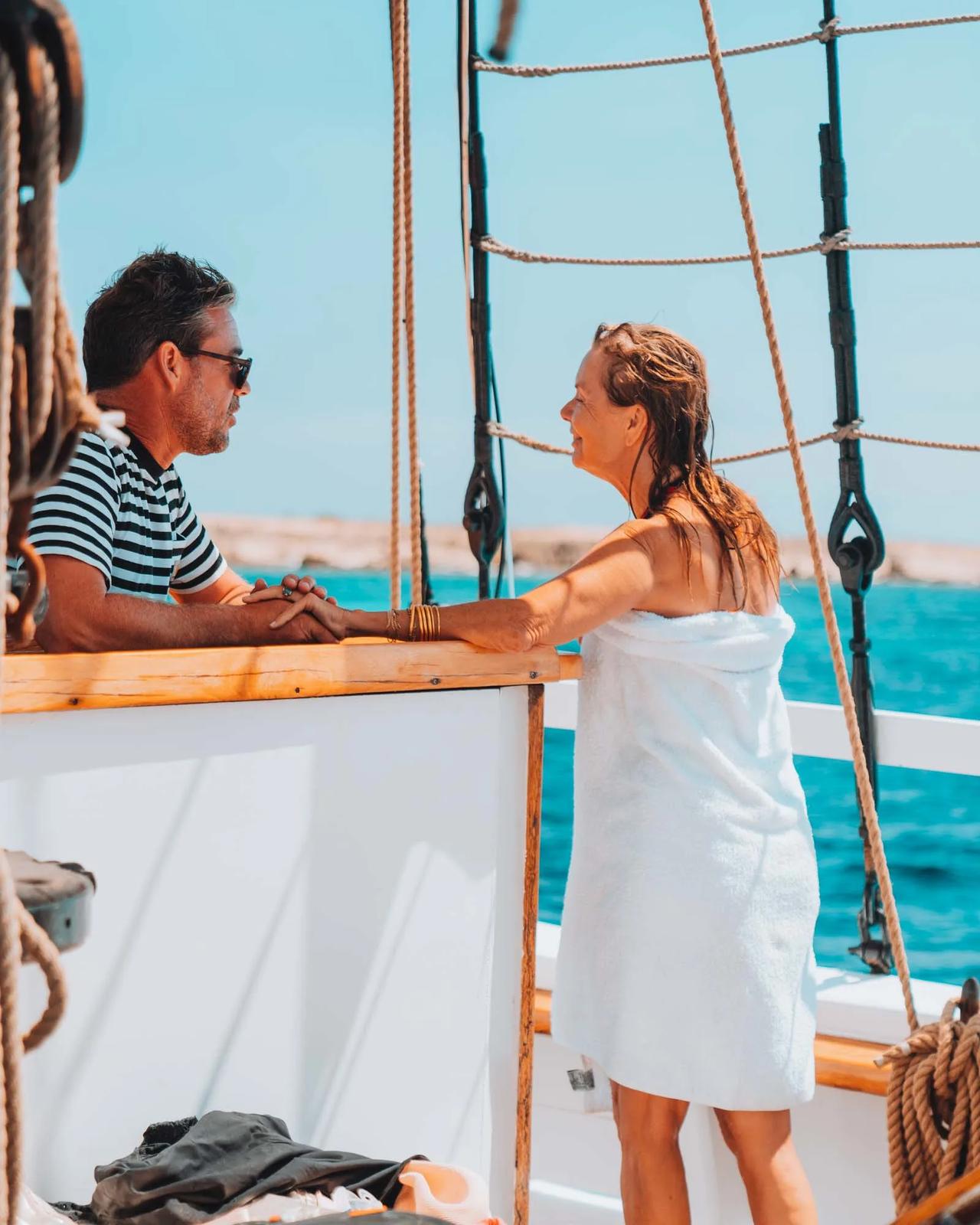 A man and a woman chatting on a boat, with the sea in the background.