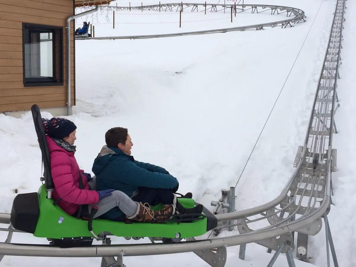 Deux personnes sur une luge d'été sur rail dans la neige.