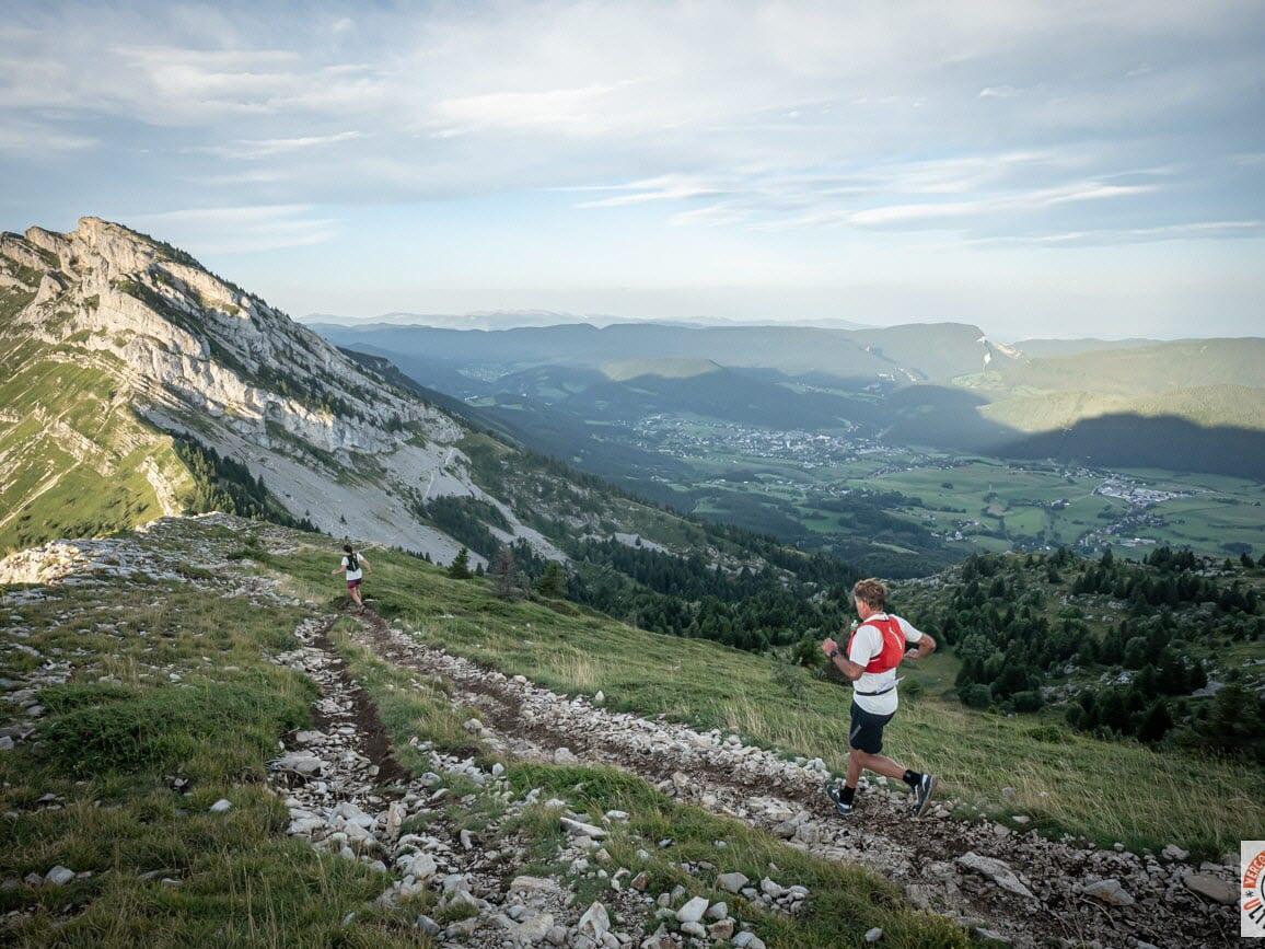 Couple de coureurs sur un sentier de montagne avec vue panoramique.