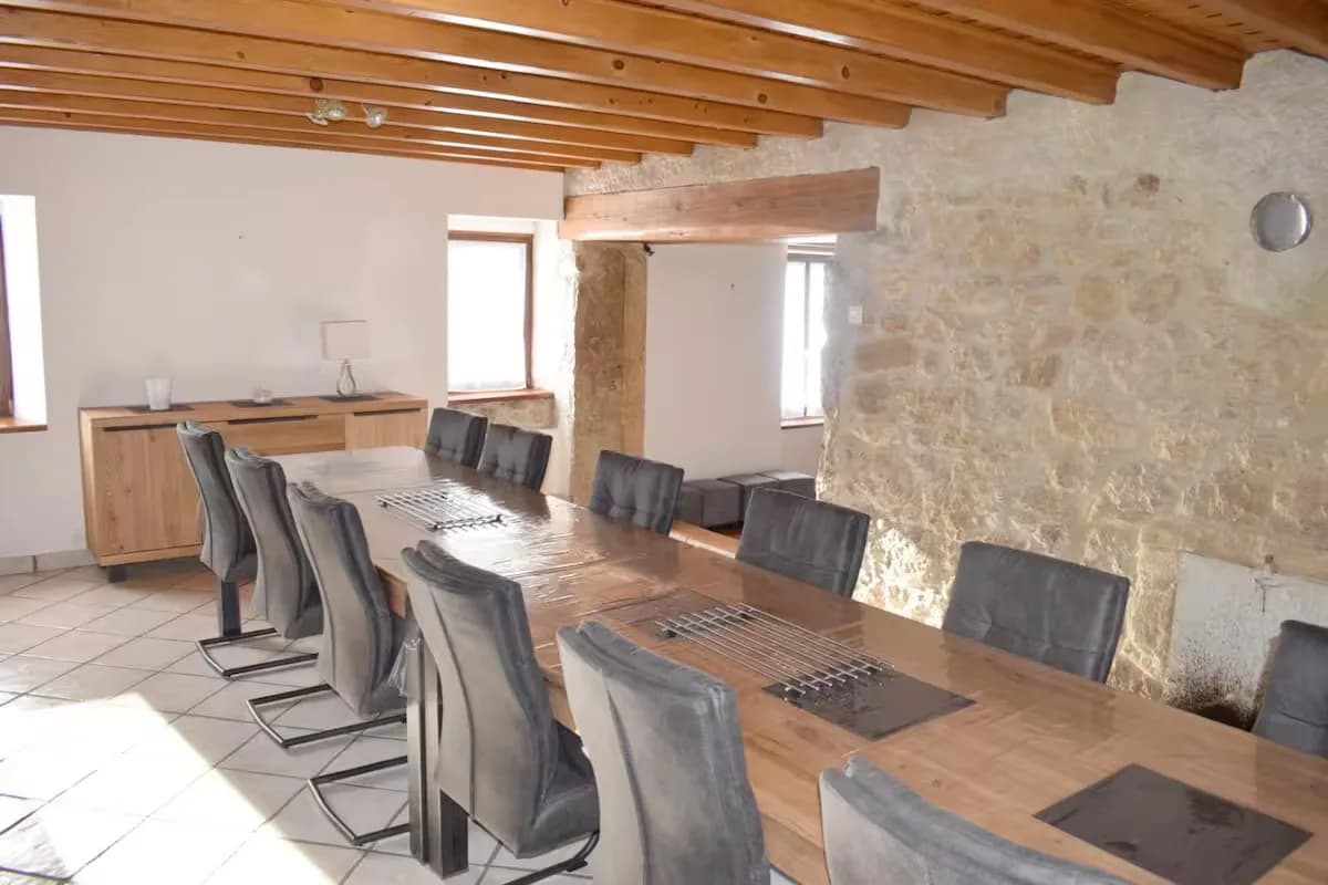 Salle à manger spacieuse avec une grande table en bois et des chaises grises.