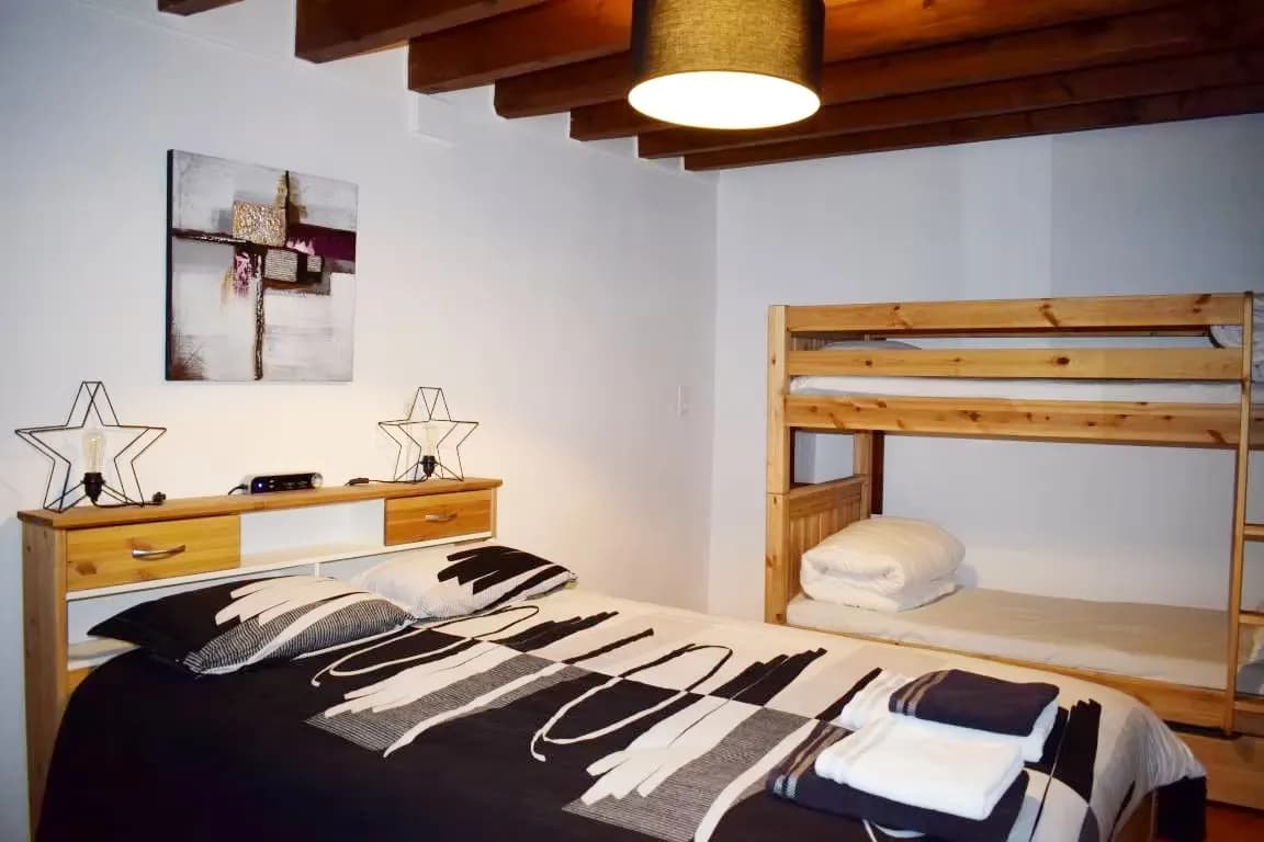 Chambre avec lit double et lit superposé en bois.