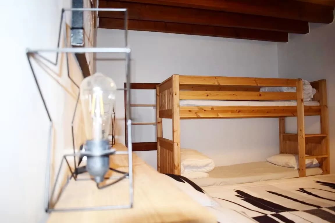 Chambre avec lit superposé en bois et lampe vintage.