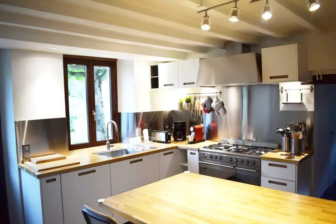Cuisine moderne avec des surfaces en acier inoxydable et un plan de travail en bois.