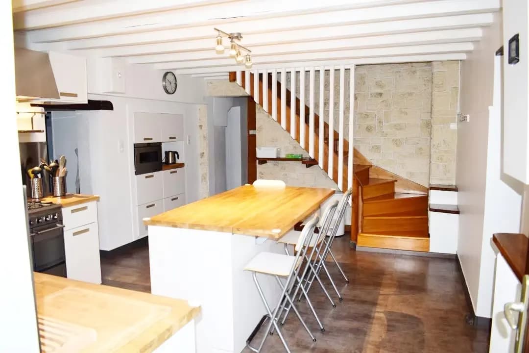 Cuisine moderne avec un îlot central et un escalier en bois.