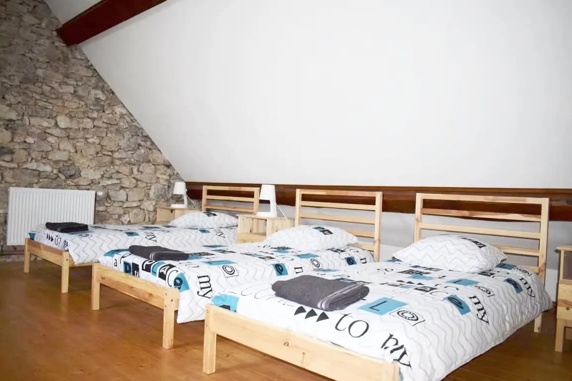 Chambres avec lits en bois et draps à motifs dans un cadre rustique.