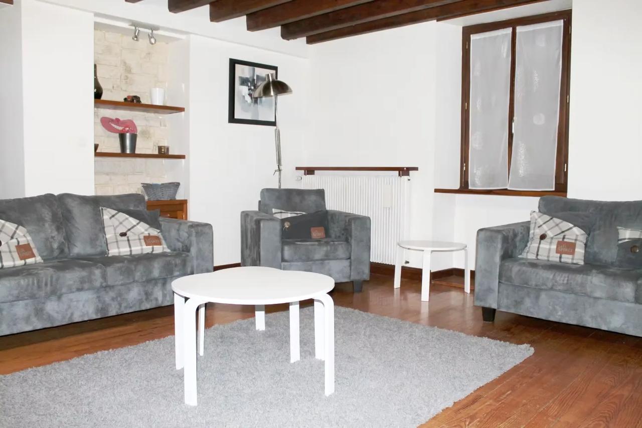 Salon moderne avec canapés gris et table blanche.