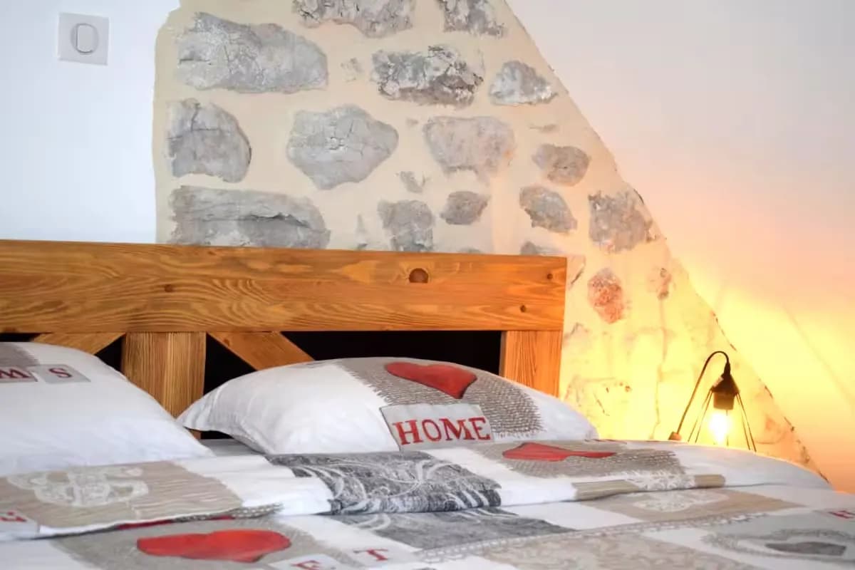 Lit avec des oreillers décorés dans une chambre au mur en pierre.