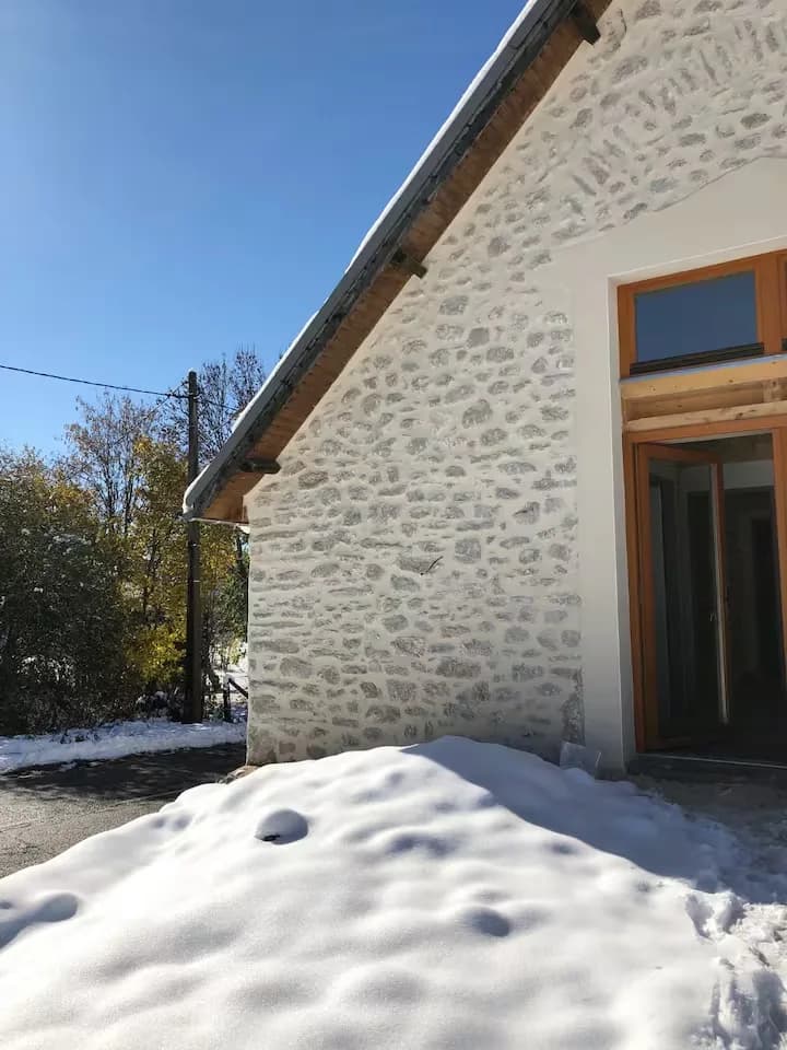 Maison en pierre avec un toit en pente et de la neige au sol.