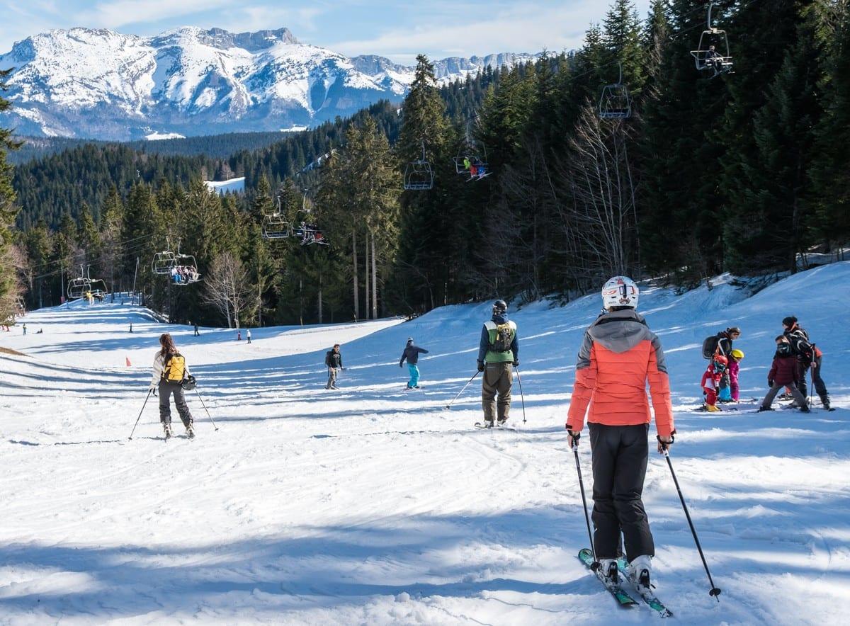 Piste de ski avec des skieurs et des télésièges en arrière-plan.