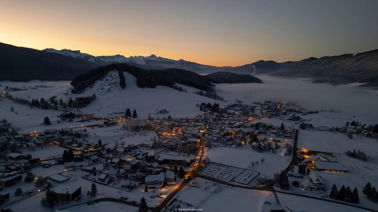 Vue aérienne d'Autrans sous la neige au crépuscule.