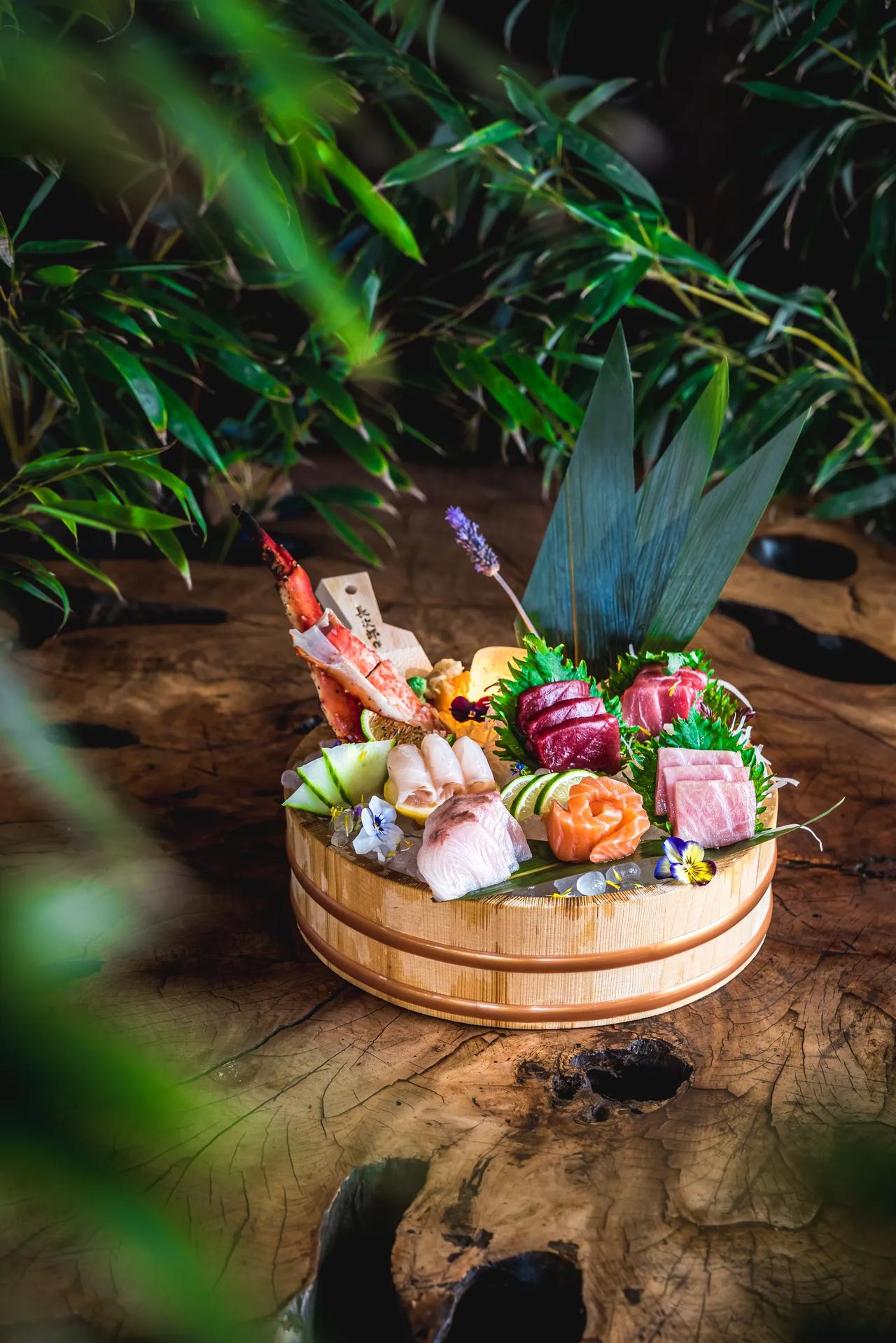 A beautifully arranged sushi platter with various seafood and garnishes.