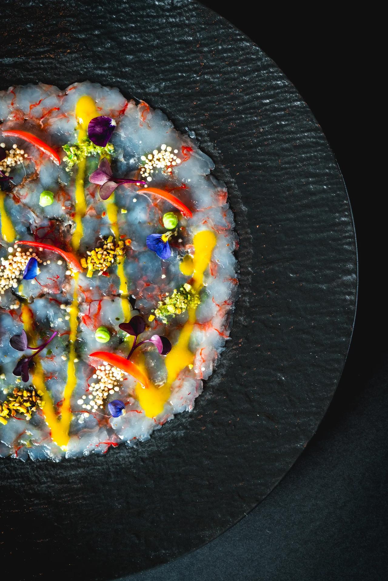 A beautifully plated dish featuring raw seafood with vibrant garnishes.