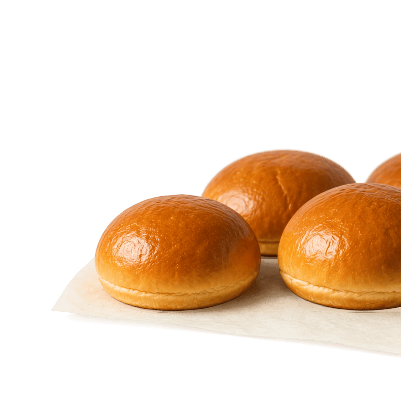 Quatre petits pains ronds dorés sur du papier parchemin.