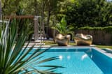 Golden sculptures beside a swimming pool in a lush garden.