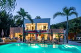 Modern villa with pool and palm trees at dusk.