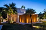 Modern villa exterior with palm trees at night.